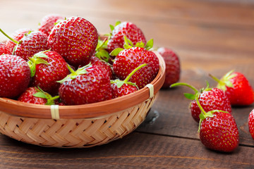 Very beautiful background with fresh strawberries in a wicker round osier basket on old brown...