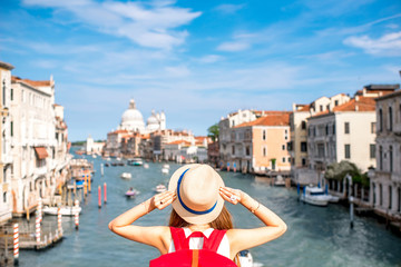 View on Grand canal with woman traveler in hat on Academia bridge in Venice. Back view with copy space - obrazy, fototapety, plakaty