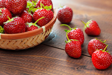 Very beautiful background with fresh strawberries in a wicker round osier basket on old brown...