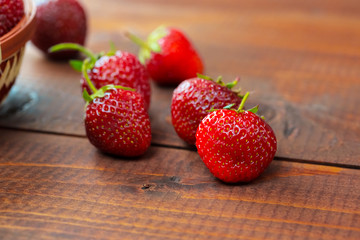 Very beautiful background with fresh strawberries in a wicker round osier basket on old brown...