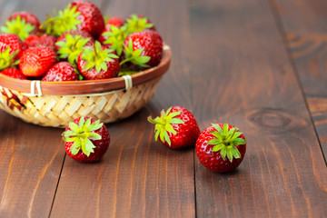 Very beautiful background with fresh strawberries in a wicker round osier basket on old brown wooden background