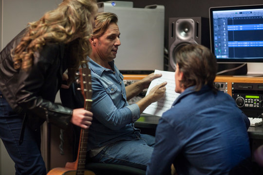 Musicians talking with music producer in music studio