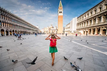 Türaufkleber Junge weibliche Reisende mit Hut und Rucksack, die auf dem Markusplatz mit Turm und Basilika im Hintergrund in Venedig stehen. Rückansicht mit Kopienraum © rh2010