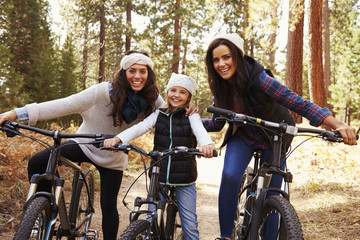 Naklejka premium Female parents cycling with their daughter in a forest