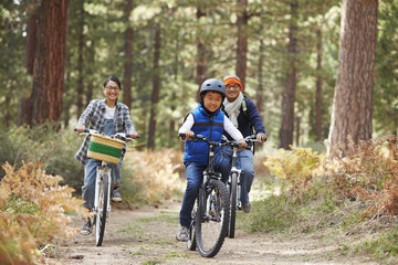 Fototapeta na wymiar Asian couple and son cycling in a forest, front view