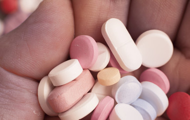 Macro photograph of various colorful medicinal pills - holding pills in the hand