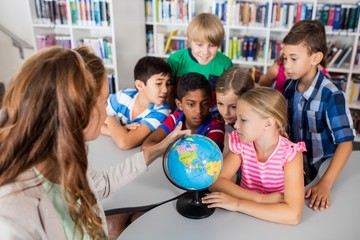 Fototapeta premium Teacher and pupils looking at a globe