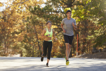 Caucasian woman and man jogging sur une route de campagne