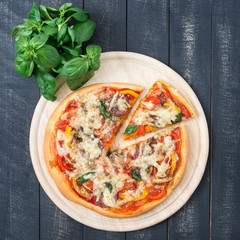 Italian pizza with cherry tomatoes, pepper, salami and basil on