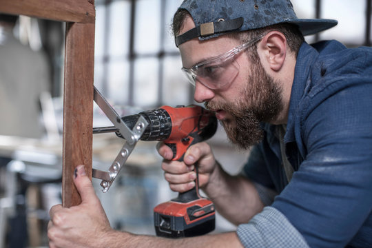 Carpenter drilling framework in antique restoration workshop