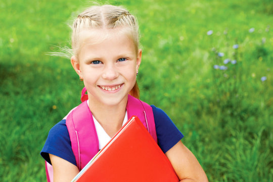 Portrait of a smiling schoolgirl in a blue school dress, with bo