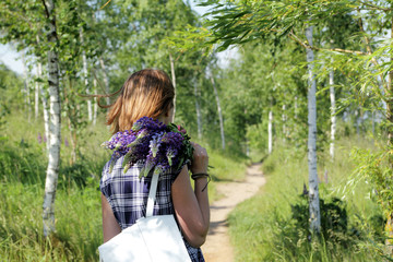 outdoor recreation / girl in a summer dress walking with a bouquet flowers on the forest path 
