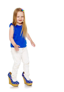 Happy little girl with long blond hair, put on the legs of mom's shoes that she doesn't come in my size-Isolated on white background