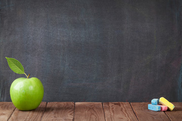 Apple fruit and chalks on classroom table
