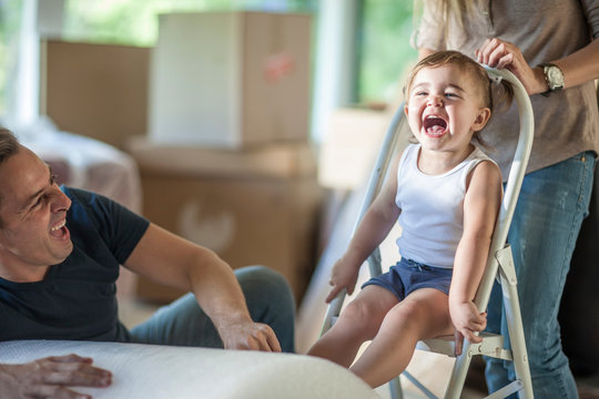 Moving house: father and daughter laughing, daughter sitting on step stool