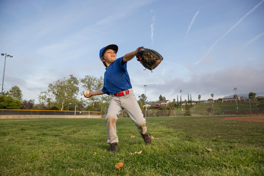 Boy throwing ball at practise on baseball field