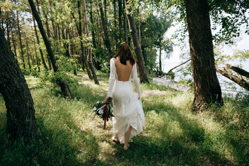 The bride in a white vintage dress walking in the woods