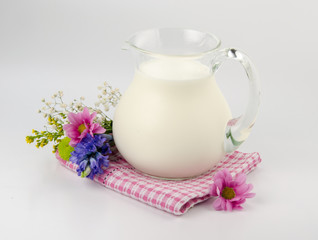 Obraz na płótnie Canvas Pitcher of milk with flowers on pink cloth