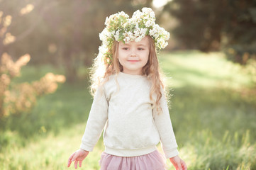 Smiling kid girl 5-6 year old with flower hairstyle outdoors. Stylish child.