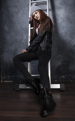 Fashion shot beautiful sexy girl in jeans and leather jacket on ladder