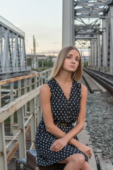 girl sitting waiting for the train looking into the distance the rails of the bridge Peron