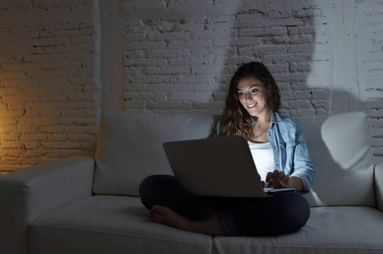 attractive relaxed woman at home sitting happy on couch using laptop at night