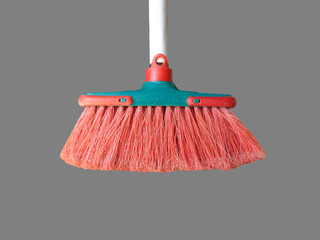 Brush for sweeping the floor with red bristles and white handle, isolated on grey background