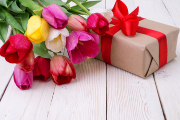 bouquet of tulips with a gift on rustic wooden board