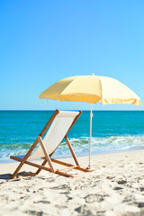 Back View Of Deckchair, Sun Lounger Under Umbrella On Sand Beach.