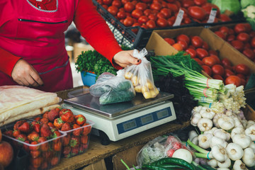 the seller is weighing vegetables on scales on the market summer day