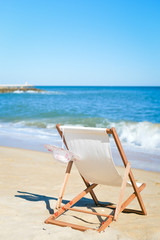 Fototapeta na wymiar Female hat and deckchair on the beach vacation, sunny background outdoors 