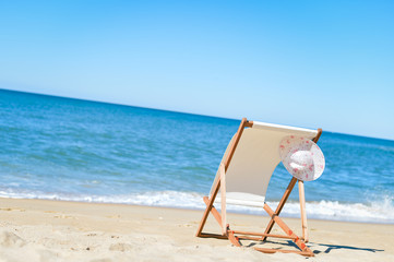 Female hat and deckchair on the beach vacation, sunny background outdoors 