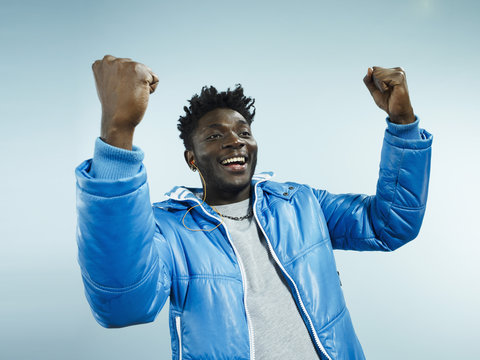A young hip man with his arms raised in celebration