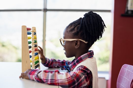 Schoolgirl using a math abacus in classroom