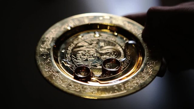 Close up of wedding rings of newlyweds during the consecration of holy water in the church before the wedding ceremony