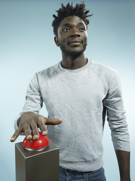 A hip young man with his hand poised above a red game show buzzer