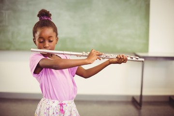 Schoolgirl playing flute in classroom © WavebreakMediaMicro