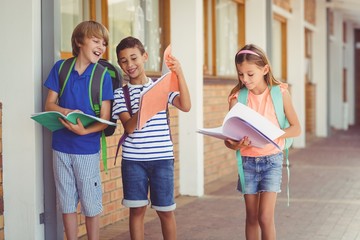 School kids reading books while walking in corridor