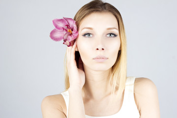 Naklejka premium Beauty woman with pink flower in hair. Clear and fresh skin. Beauty face.