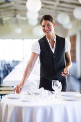 Portrait of smiling waitress setting the table