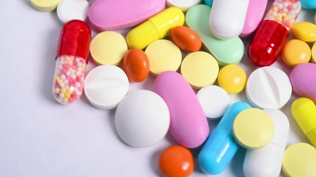 Different colorful pills rotation on light background, looped video