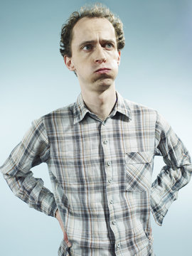 A man with puffed cheeks looking away with uncertainty