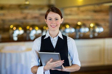 Portrait of smiling waitress holding digital tablet