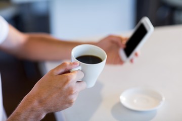 Man having cup of coffee while texting
