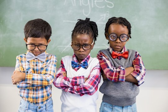 Portrait Of Three School Kids Standing Against Chalkboard