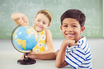 Happy school kids with globe in classroom