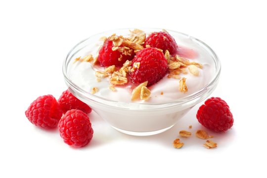 Clear bowl of raspberry flavored yogurt with granola and berries over a white background