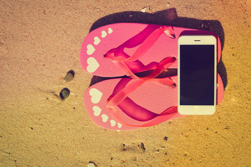 Closeup on smartphone and flip-flops on beach background. Top view style, photo and video outside