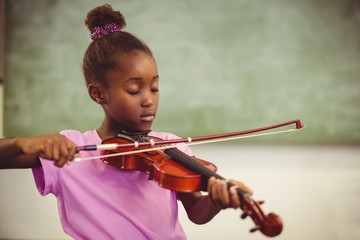 Schoolgirl playing violin in classroom