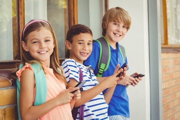 Portrait of school kids using mobile phone in corridor